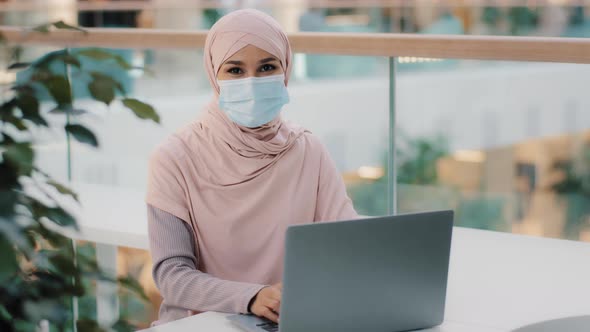 Young Arab Woman in Hijab in Medical Mask Works on Laptop Approving New Computer Application Shows