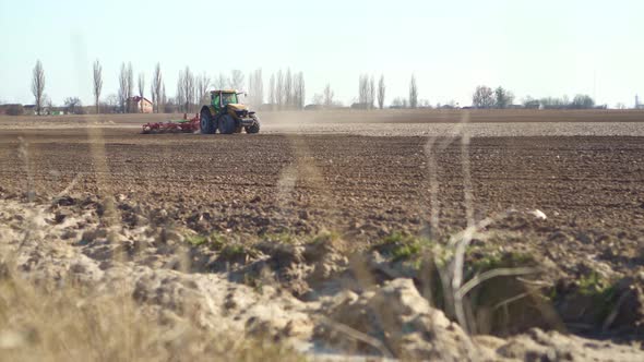 The Tractor Drives Across The Field Plowing The Ground.