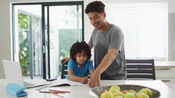 Happy biracial man and his son doing homework together