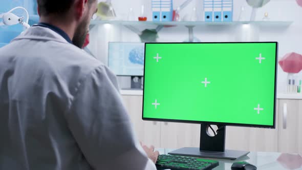 Zoom in Shot on Doctor Typing on Green Screen Computer