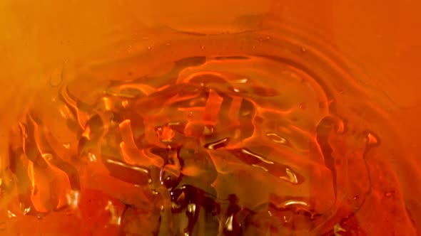 Slow motion abstract footage of the ebb and flow of a bright, orange, oily liquid