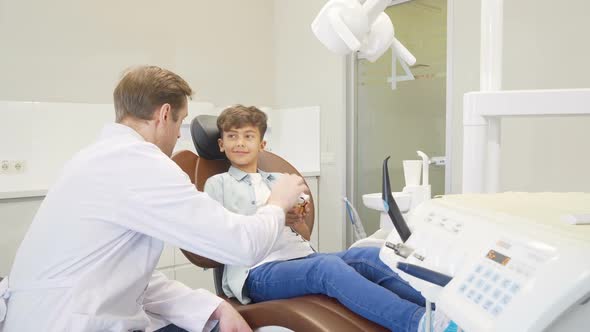 Male Dentist Educating Little Boy About Dental Hygiene