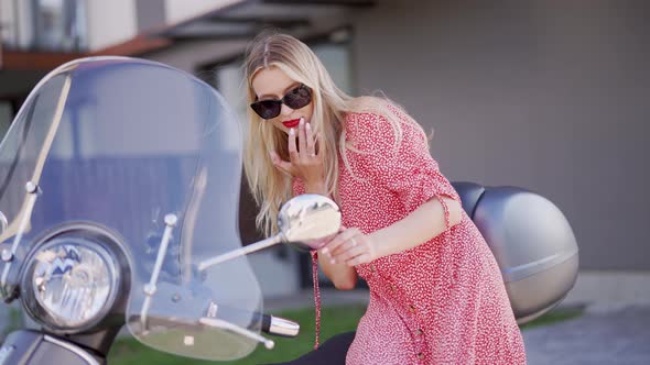 Young Woman Correcting Makeup Near Scooter