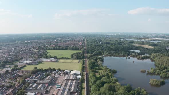 Follow drone shot over British rail train along long straight track in the countryside