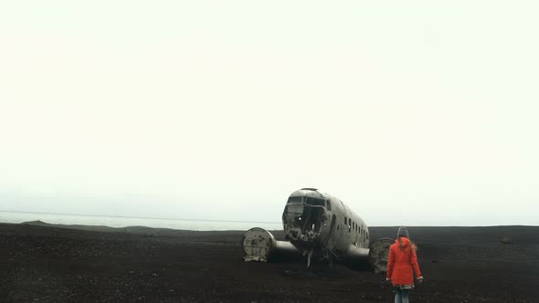 Young Traveling Woman Walking Alone on the Black Beach Near the Breaker DC3 BMC Plane in Iceland