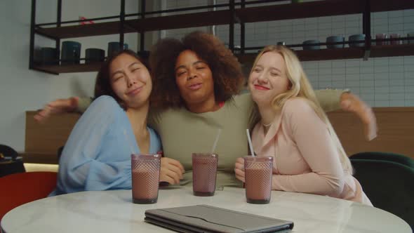 Joyful Pretty Multiethnic Female Friends Embracing at Cafeteria