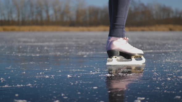 Young Woman Ice Skating on a Frozen Lake on a Freezing Winter Day. Legs of Skater on Winter Ice Rink