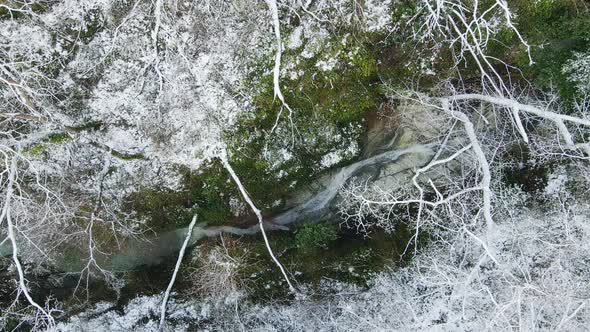 Stream of Water Flowing Among the White Rocks in the Forest in Winter