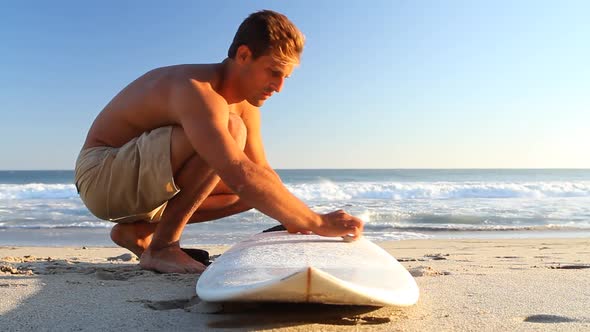 A surfer waxing board before surfing