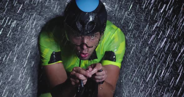 Triathlon Athlete Riding a Professional Racing Bicycle on an Intense Workout in Dark with Rain