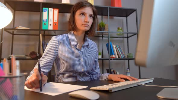 Thinking woman turning pencil at office desk