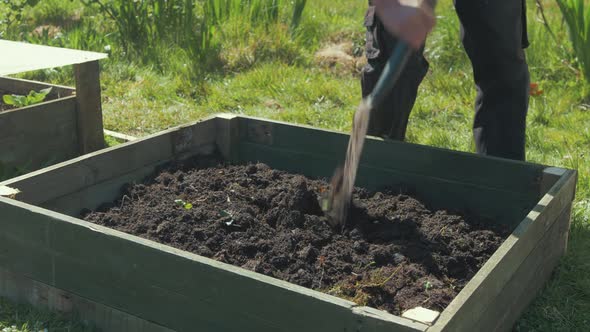 breaking up soil with shovel raised garden bed