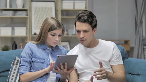 Happy Young Couple Celebrating Success While Using Tablet