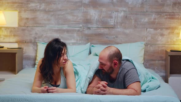 Young Couple Laying in Bed Wearing Pajamas