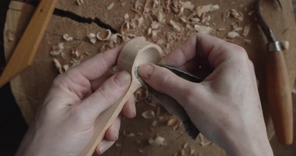 Woman Carpenter Polishes Wooden Spoon with a Sandpaper Close-up