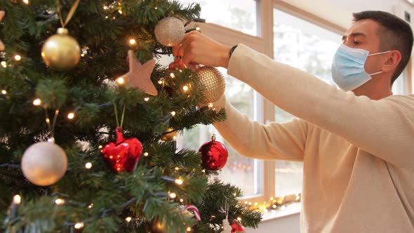 Man in Mask Decorating Christmas Tree at Home