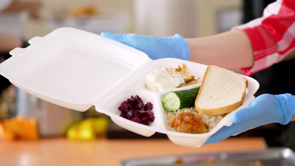 Close-up, Female Hands in Gloves Hold Foam Lunchbox with Charity Hot Meal for Poor, Homeless People