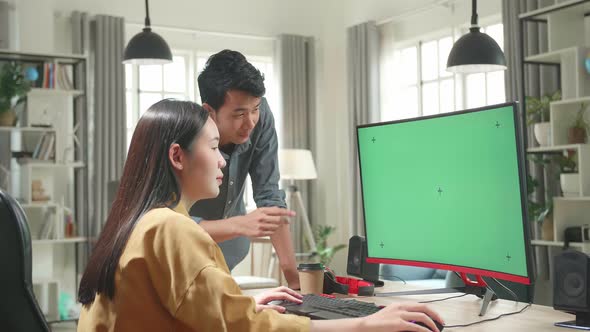 Female Works With Her Male Colleague On A Project On Her Personal Computer With Mock-Up Green Screen