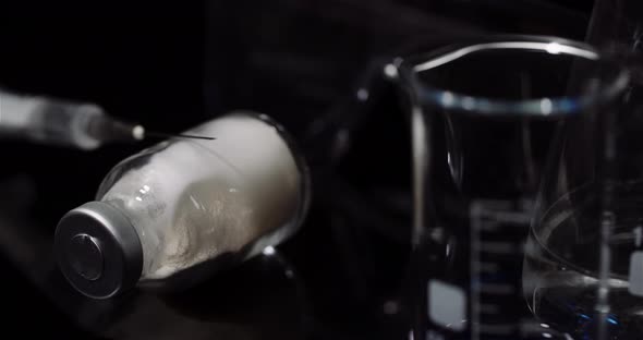 Laboratory Equipement: Syringe and Medicine, Test Tubes and Flasks Rotating on Black Background alt