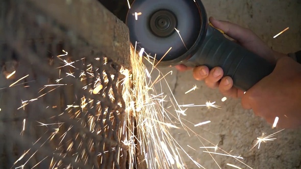 Closeup of worker using a grinder cuts metal in a workshop