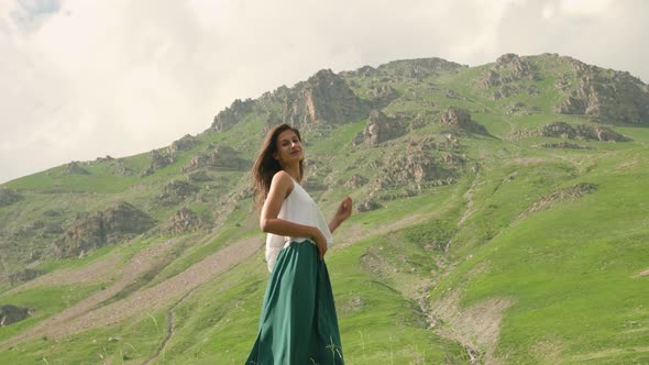 Beautiful woman posing in front of a green mountain in the distance in Barcelonnette, France.