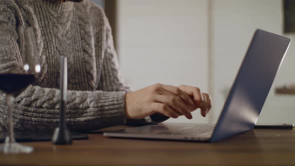 A Young Handsome Man in Glasses Works on a Laptop