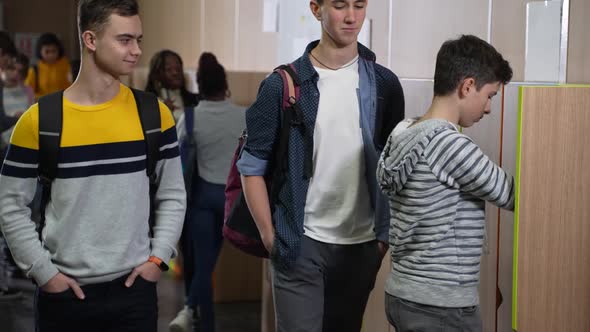 Classmates Bullying Schoolboy Standing Near Locker