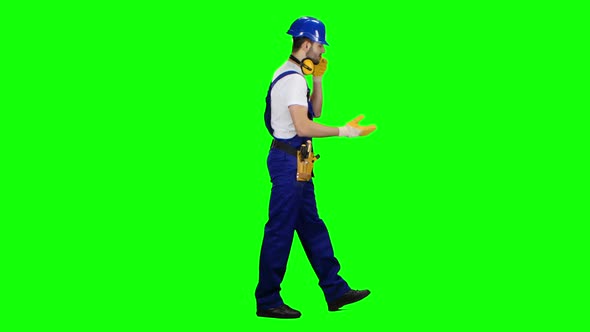 Builder Speaks on the Phone and Screams at His Subordinates. Green Screen. Side View