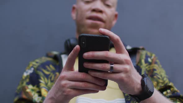 Thoughtful albino african american man with dreadlocks using smartphone