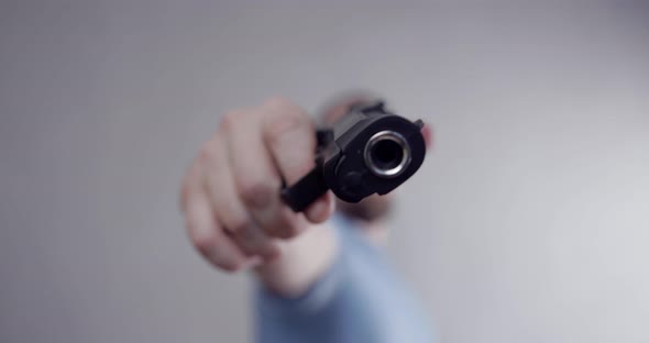 The man threatens with a pistol, points the pistol at the camera. Close-up barrel of a pistol.