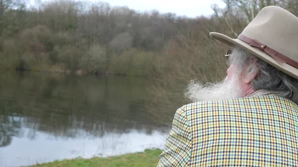 An elderly man calmly looking out over the lake