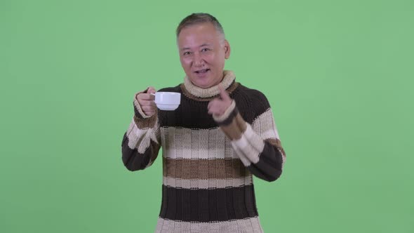 Happy Mature Japanese Man Holding Coffee Cup and Giving Thumbs Up