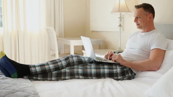 Man using laptop in the bedroom at home 4k