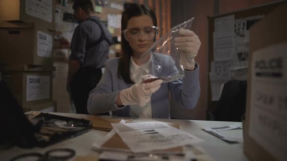 Expert Lady Examining Bloody Knife From Murder Scene and Writing Results Report