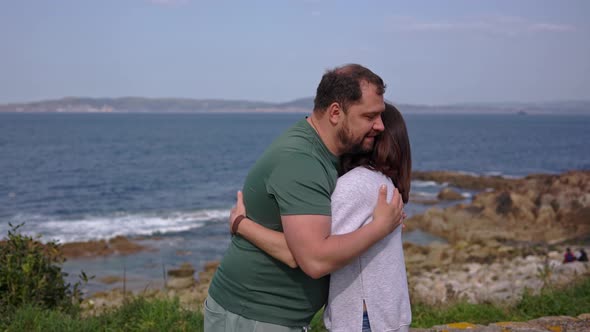 A Man and a Girl Couple Hug and Kiss Against the Backdrop of the Ocean