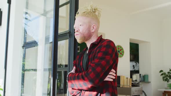 Thoughtful albino african american man with dreadlocks looking at the window