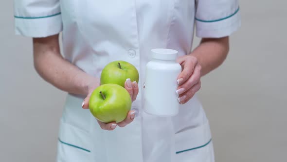 Nutritionist Doctor Healthy Lifestyle Concept - Holding Organic Green Apple and Jar of Vitamin Pills