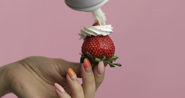 Woman Hand Holds Strawberry and Squeeze Out Whipped Cream on Top of the Berry