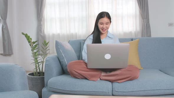 Asian Woman Sitting Sofa And Use Laptop Computer In Home Living Room