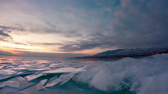 A city across a frozen lake with rafted ice in the foreground - sunrise time lapse