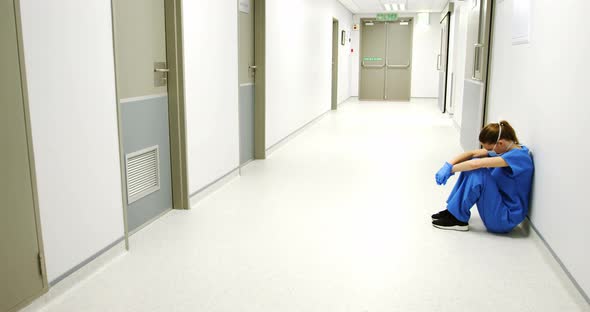 Tensed female doctor sitting in corridor