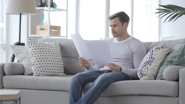 Penisve Adult Man Reading Documents While Sitting on Couch