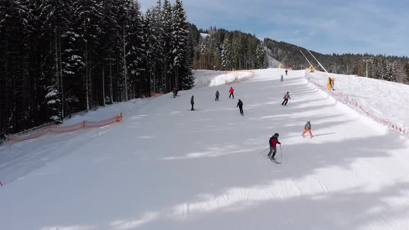 Aerial View Lot of Skiers Go Down the Ski Slopes. Drone Flies Low Next To Skiers