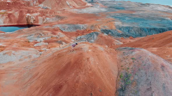 A Man Tourist Running Up on an Orange Clay Mountain