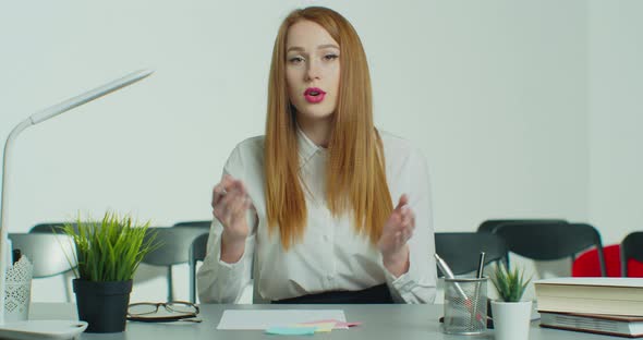 Young Redhead Woman in Glasses Has Online Business Conference Call