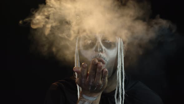 Sinister Man with Horrible Halloween Skeleton Makeup Making Fly Air Kiss with Smoke. Day of The Dead