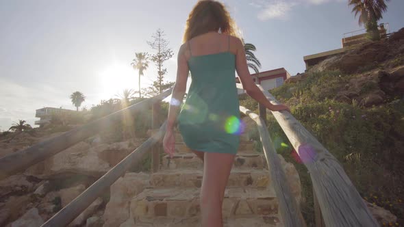 Back View. Young Woman Go From the Beach Climbing Up the Stairs. A Woman Walk Up the Stairs
