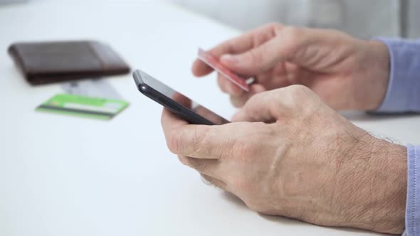 The Hands of a Man Who Holding a Smartphone a Credit Card Makes a Successful Payment