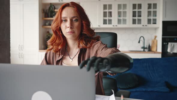 Independent Happy Disabled Girl Closes the Lid of a Working Laptop with a Prosthetic Hand