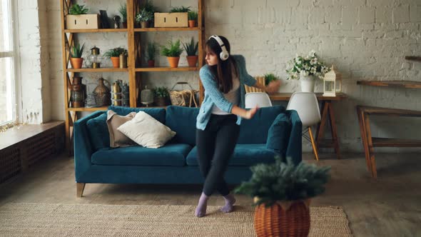 Joyful Young Woman Is Dancing at Home Listening To Music Through Headphones Having Fun and Enjoying